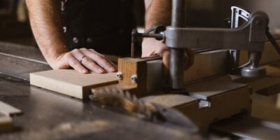 Woodworker guiding wood through table saw in workshop